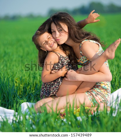 Happy girls embrace and playing on green grass at spring or summer park picnic