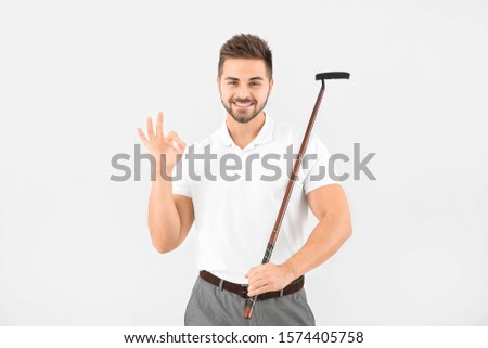 Handsome male golfer showing OK on light background