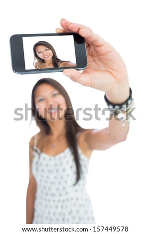 Smiling asian woman taking a selfie using her smartphone