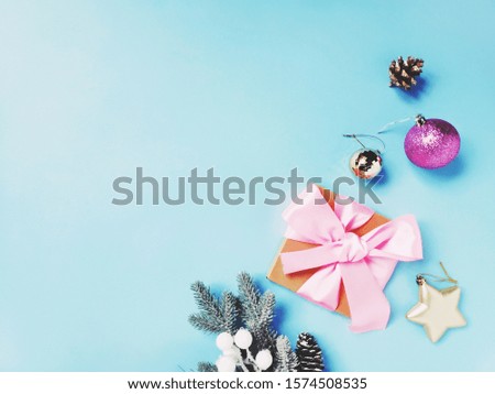 Fir tree branch, wrapped gift box, balls on a light blue background. Flat lay Christmas photo. New Year present and decoration