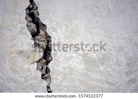 Big crack on the gray wall, abstract image of the vertical cleft. Close up. Selective focus. Copy space. Royalty-Free Stock Photo #1574522377