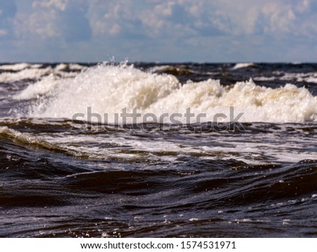 blurred foreground with sparkling waves, clouds and sea in the background