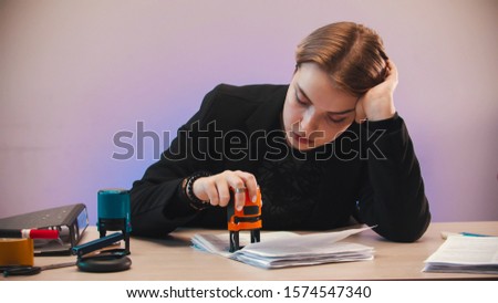 office - a bored woman putting a stamp on the document