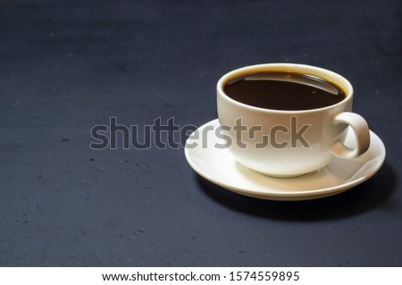 white cup with a coffee on a black background, top view, selective focus