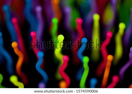 Abstract background of colorful waves in motion on black. Bokeh of defocused curves, blurred neon blue, yellow and red leds, imitation of glowing sperm flow, wallpapers and banners