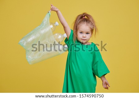 Caring for the environment. Little girl is separate plastic trash to recycle. Bright color studio background