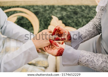 bride and groom holding hand together with beautiful ring  and hand full of henna blury bakcground