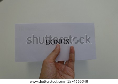 closed up hand holding white envelope with Bonus text on it.