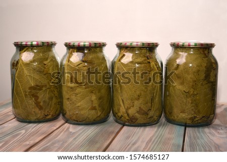 Grape leaves rolled up in glass jars standing in a row on a wooden background