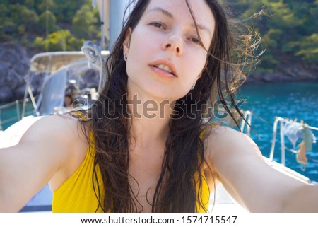Selfie portrait of a positive multi-ethnic girl in a yellow swimsuit on Board a yacht. Boat trip