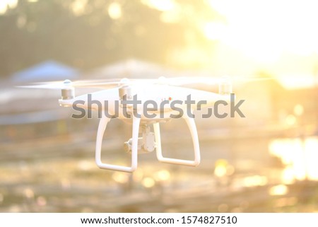 White drone flying for take aerial photo. at sunset evening orange sky.