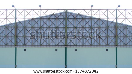 the green steel structure of an empty billboard frame with spotlights is installed in front of the factory with an aluminum sheet roof. 
For rent. 