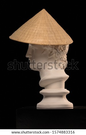 White plaster Statue of a bust of Apollo Belvedere in an Asian conical hat on colorful backgrounds