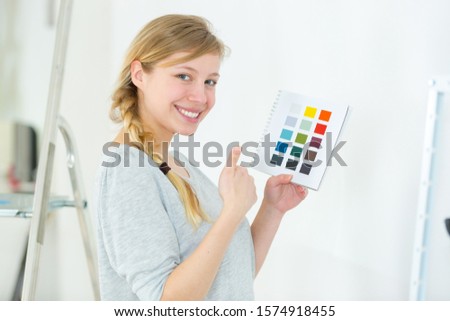 woman selecting home interior paint color from swatch catalog