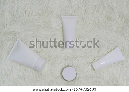 Cosmetic bottle container with a white carpet background on top view.