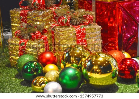 Gold colour present boxes and shiny colourful balls on green floor decorate for Christmas time