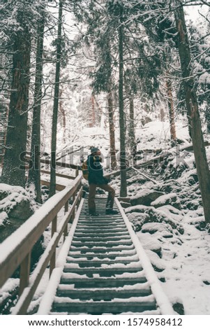 Picture of man in winter forest on wooden bridge .