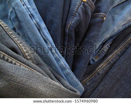  Stack of blue jeans. Heap or pile of old jeans background.                              