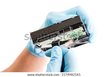Repairman hand in blue runnber glove holds computer hard drive disk with green chip.