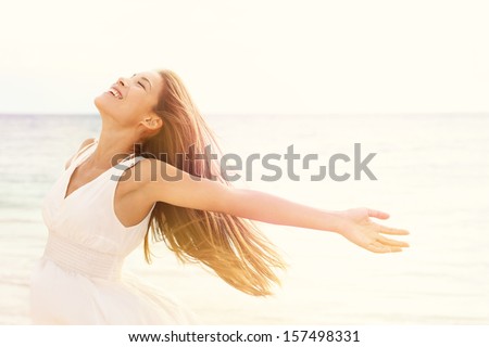 Freedom woman in free happiness bliss on beach. Smiling happy multicultural female model in white summer dress enjoying serene ocean nature during travel holidays vacation outdoors.