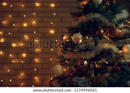 Christmas tree festive twilight lighting interior decoration toys and garland yellow illumination on brick wall background winter holidays copy space for your text 