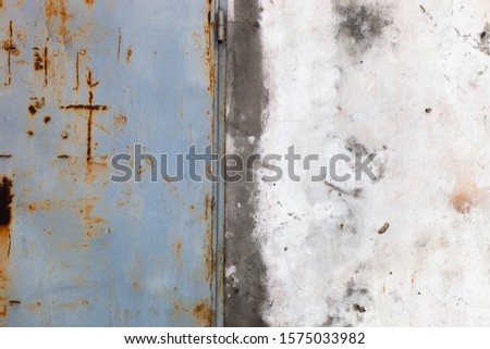 Background. Old worn wall of light and dark color with a metal door.


