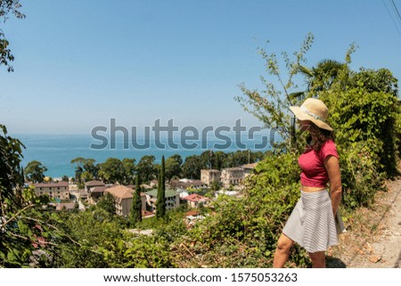 A girl stands on the edge of the mountain and looks at the sea