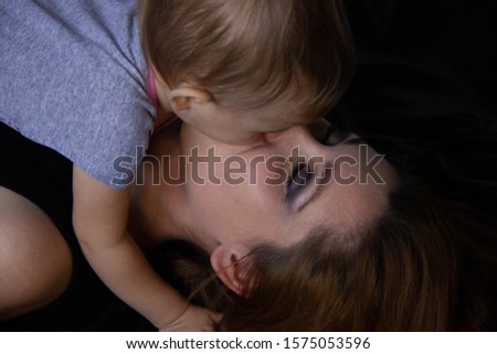 Mom hugs with her baby and kiss on a black background. Happy childhood.