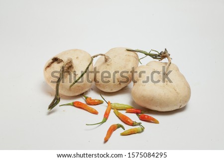 three bengkoang and some red chili on a bamboo plate with an isolated white background