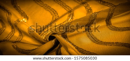 ornament of the decor, the fabric is transparent mustard yellow with brightly congenital stripes, the material allowing the light to pass through it so that the objects behind are clearly visible