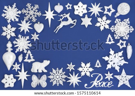 Christmas silver peace sign with tree decorations & white frosted baubles forming an abstract background on blue with copy space. Traditional symbols for the festive season.