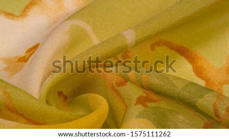 Texture, background, thin translucent silk with a large pattern. On a yellow background - lettuce and orange flowers, each with its own pattern, which makes the overall composition a bit abstract. Royalty-Free Stock Photo #1575111262