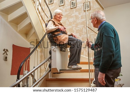Elderly Couple in the Staircase with Stairlift Royalty-Free Stock Photo #1575129487