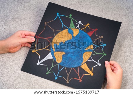 Child holding picture of Group of people around the world. Pencil drawing.