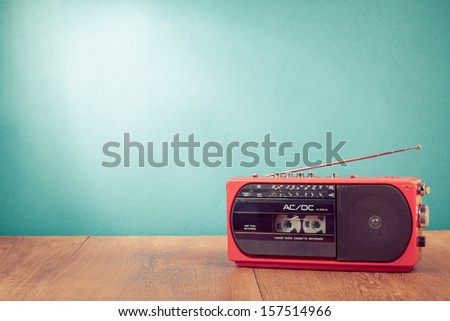Retro red radio cassette player on table in front mint green background