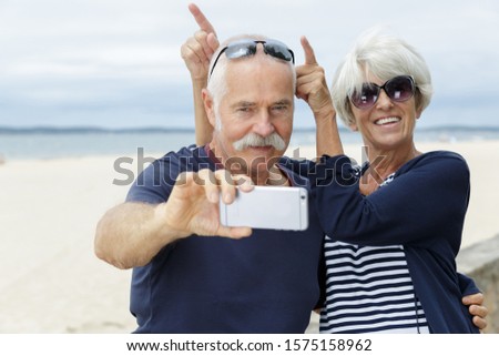 senior couple taking selfie on the beach