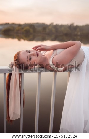 Girl ballerina with long hair lies on a white fence