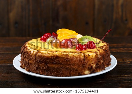 cake with cream and berries on a brown wooden background, place for text
