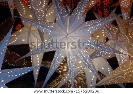 Beautiful Festive Background. Lights In Darkness. White-Silver Traditional Stars As Christmas Lanterns On The Christmas Market Of Historical Dortmund City, Germany.