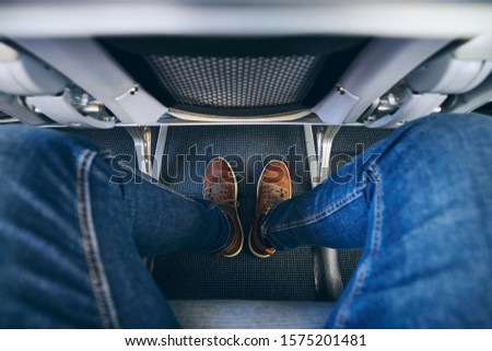 Legroom between seats in commercial airplane. Personal perspective of passenger on leg in economy class.  Royalty-Free Stock Photo #1575201481
