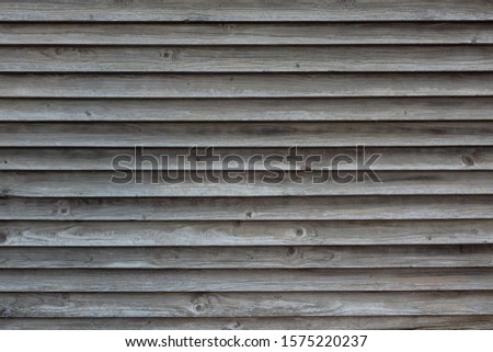 Fragment of a fence from horizontal boards superimposed on each other. The wood material cracked and turned gray from old age. Background. Texture.