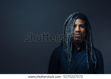 Portrait of a serious young man with cool black and gray hair in studio