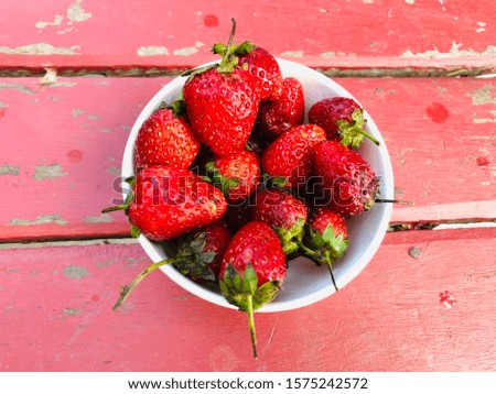 Red strawberry in bowl on wood background.