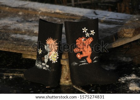 black felt boots with a pattern of a hedgehog and a bear stand on the ice
