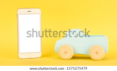 Mobile phone and children's blue toy car on a yellow background