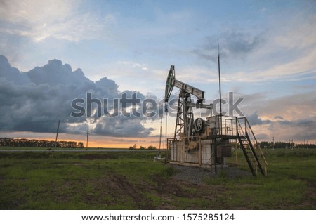 Working pumpjack in field on sunset background