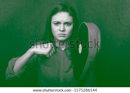 photo of a young girl with dark hair; shot of a young girl with glasses in the studio; a young girl aiming her fist at a boxing paw;