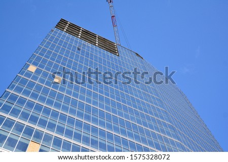 New modern office skyscraper being built in a city. Architectural facade building during construction with of glass elements finished and in concrete.