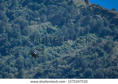 An army helicopter flying in between the mountains.