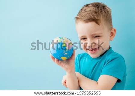 Little boy holding a globe on blue background.